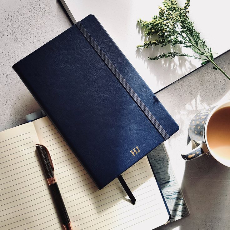 a notebook and pen sitting on top of a desk next to a cup of coffee