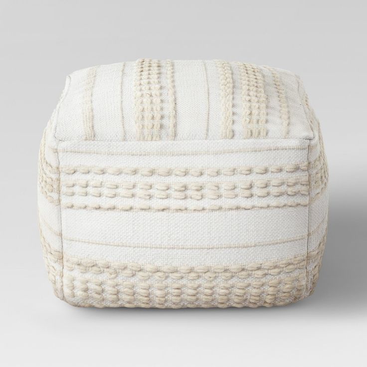 a white ottoman cushion with braiding on it