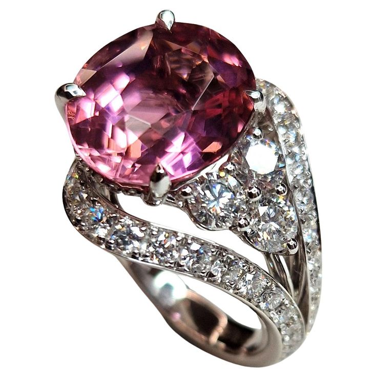 This cocktail ring has an asymmetric geometry that contrasts a beautiful pink Tourmaline on one side, with a vibrant and bright tone, oval cut ct 7.38 (from Nigeria) on the other side diamonds. The double shank structure is also completely set with brilliant-cut diamonds. The overall carat of the diamonds (color E/F clarity Vs) is 2.21ct. The name of this creation is HANAMI and takes its cue from the Japanese cherry blossom, which has bright pink petals. The stem design is meant to recall classic Japanese garden jumpers with their ticular curved lines. The whole ring is made of 18kt white gold Luxury Pink Oval Diamond Ring, Luxury Pink Oval Sapphire Ring, Dazzling Pink Oval Diamond Ring, Pink Oval Diamond Ring With Dazzling Style, Pink Oval Multi-stone Ruby Ring, Formal Pink Multi-stone Sapphire Ring, Formal Oval Pink Sapphire Ring, Modern Pink Ring For Formal Occasions, Dazzling Oval Pink Ring