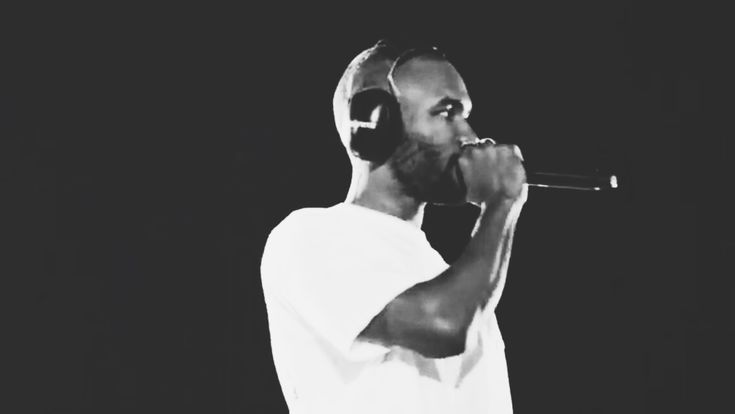 a black and white photo of a man with headphones on singing into a microphone