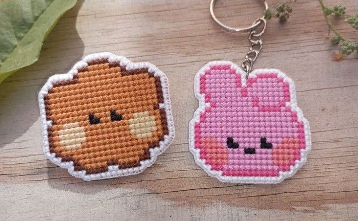 two cross stitch keychains are sitting on a table