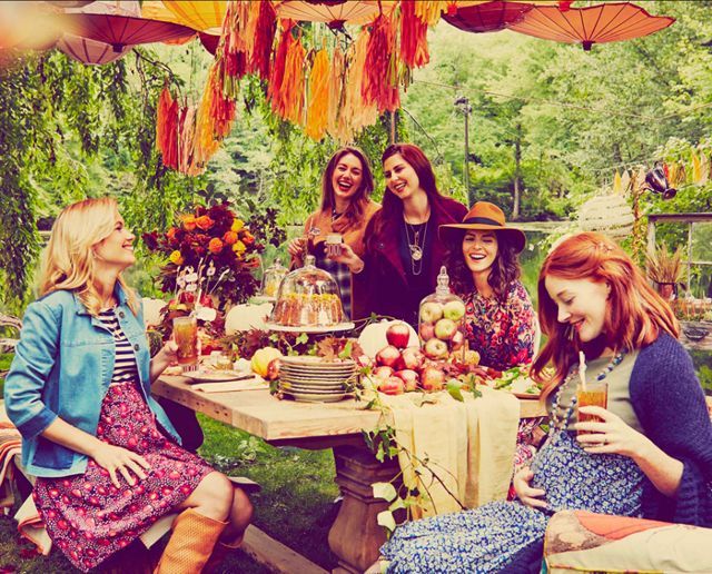 a group of women sitting around a table with food and drinks in front of them