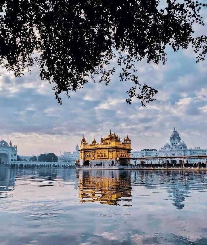 the golden building is surrounded by water and buildings in the background with clouds above it