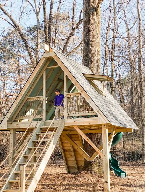 a child's play house built into the side of a tree with stairs leading up to it