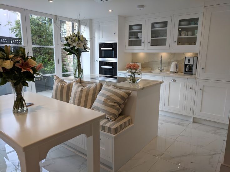 a kitchen filled with lots of white cabinets and counter top space next to a dining room table