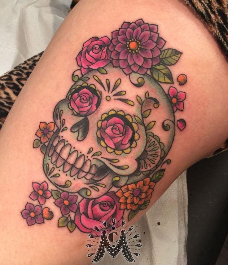 a woman's thigh with a skull and flowers on it