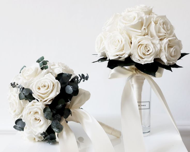 two bridal bouquets with white roses on them