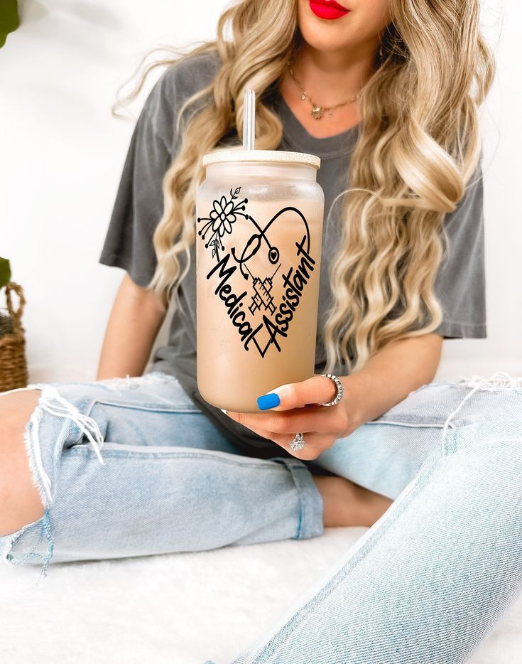 a woman sitting on a bed holding a drink in her hand with the word nurse written on it