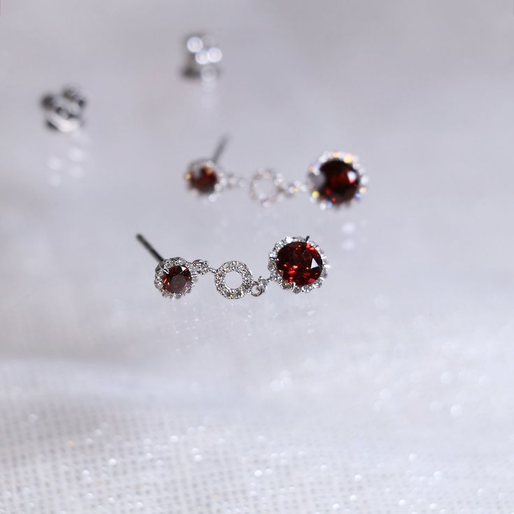 "These stylish earrings have a stunning bright color and the Garnet is surrounded by a halo of shimmering diamonds. Perfect as a gift for girlfriend or wife or mother. Features * Made to Order. * Metal: 925 Sterling Silver plated with 14K Gold * Custom Color: Rose Gold, Gold, Silver * Main Stone: Garnet,3mm dia Round Shape 2pcs, 5mm dia Round Shape 2pcs * Side Stone: Cubic Zirconia Customization is available, we also can make it with 14k solid gold (white or yellow or rose) and diamond accent st Luxury Ruby Earrings With Halo Design, Ruby Earrings With Halo Setting In Fine Jewelry, Ruby Halo Setting Earrings In Fine Jewelry, Ruby Halo Earrings In Fine Jewelry Style, Ruby Halo Setting Earrings Fine Jewelry, Ruby Halo Setting Earrings, Red Halo Design Earrings For Formal Occasions, Red Halo Earrings For Formal Occasions, Formal Red Halo Design Earrings