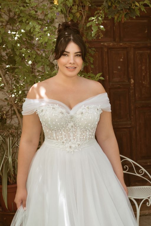 a woman in a white dress standing next to a tree and bench with her hands on her hips