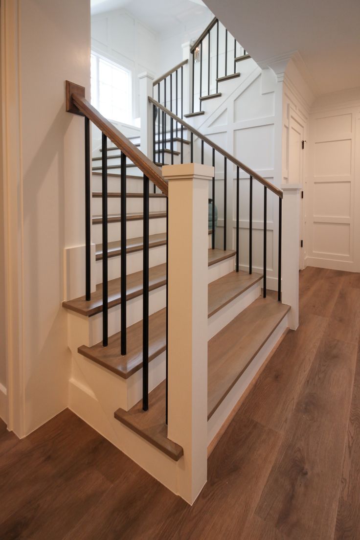 a white staircase with black handrails and wood flooring in a new home