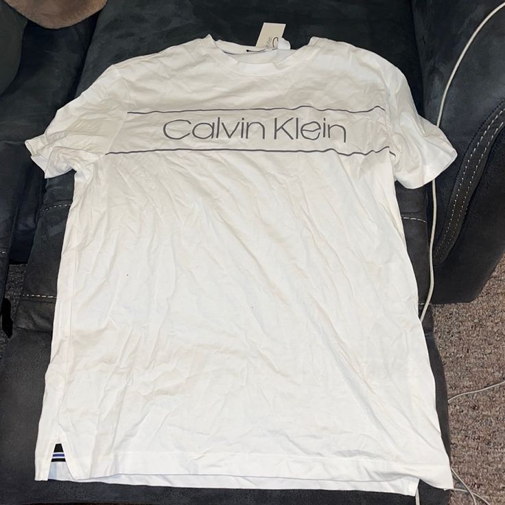 White Calvin Klein T Shirt Short Sleeve. Size Medium. Brand New With Tags Never Worn. Calvin Klein White Shirt For Spring, Calvin Klein Casual Tops For Streetwear, Casual Calvin Klein Tops For Streetwear, Casual Calvin Klein Tops With Letter Print, Casual Calvin Klein Tops With Logo Print, Calvin Klein Short Sleeve Shirt For Spring, Calvin Klein Cotton Tops For Summer, Calvin Klein Graphic Tee For Spring, Casual Calvin Klein Top With Logo Print