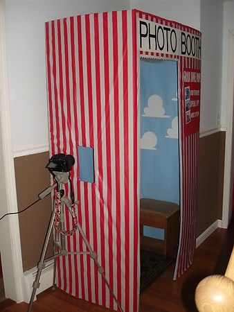 a red and white striped photo booth with a camera on a tripod in front of it