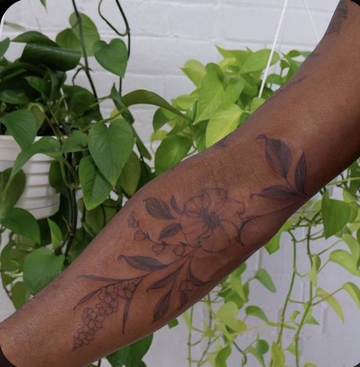 a person with a flower tattoo on their arm next to a potted green plant