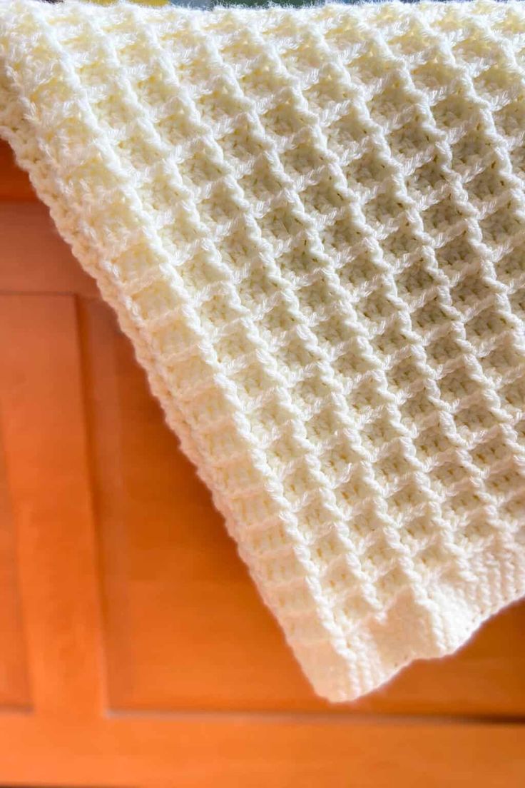 a white crocheted blanket sitting on top of a wooden floor next to a door