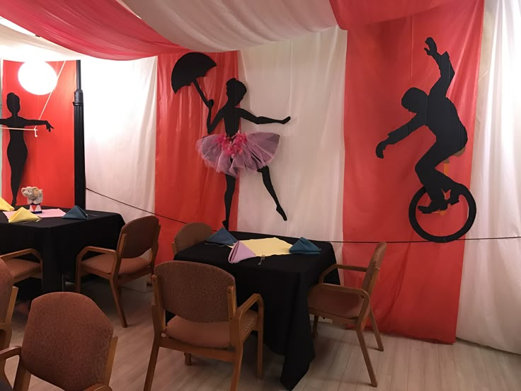 a room filled with tables and chairs covered in black cloths, decorated with silhouettes of dancers