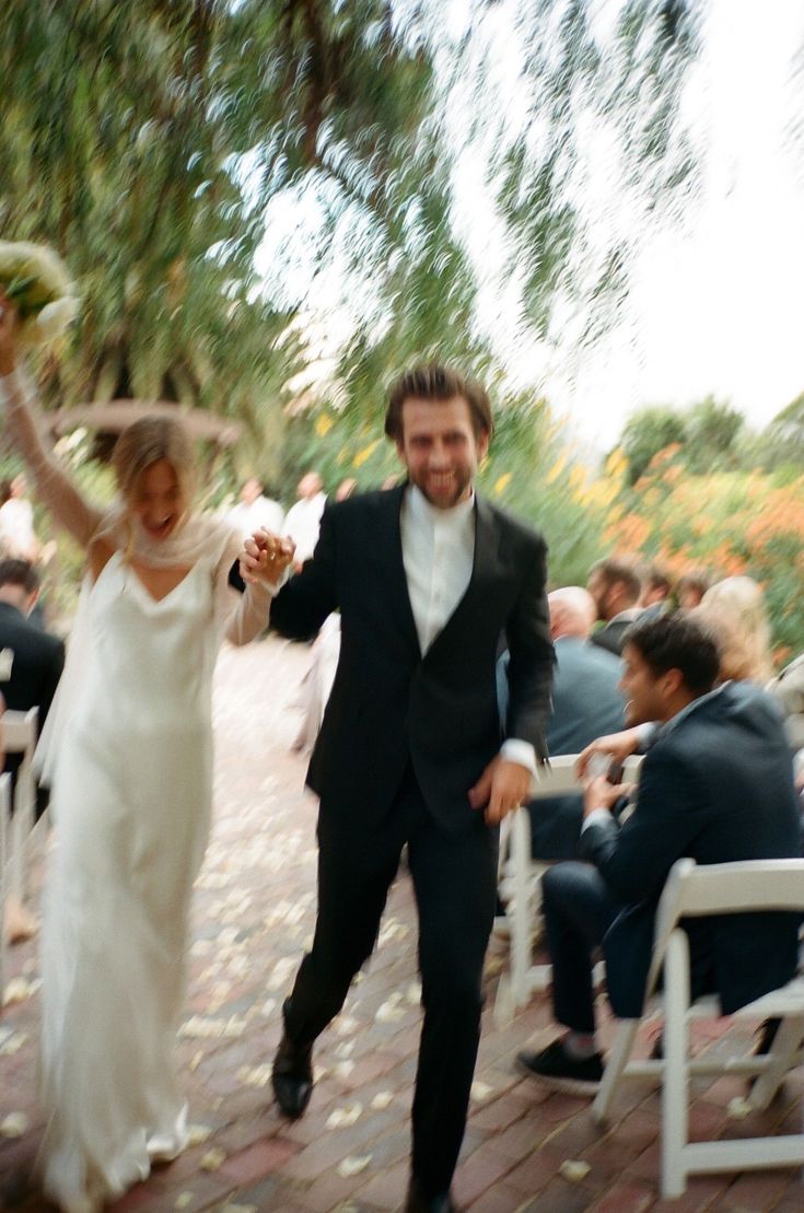 a bride and groom walking down the aisle after their wedding ceremony at an outdoor venue