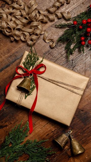 an old envelope tied with red ribbon and bells on a wooden table next to christmas decorations