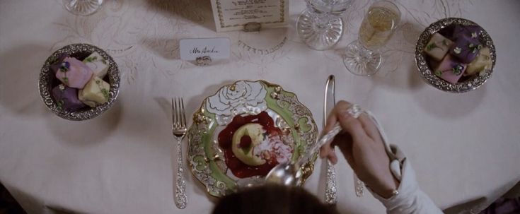 a person is sitting at a table with plates and silverware on top of it