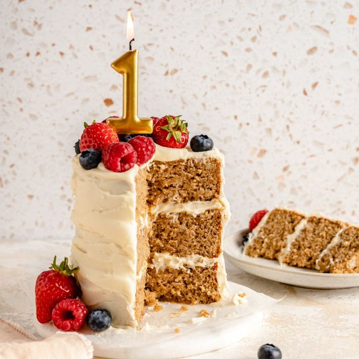 a slice of cake with white frosting and berries on the side