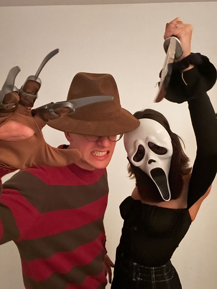 two people dressed in costumes with masks on their faces and one wearing a mask behind them