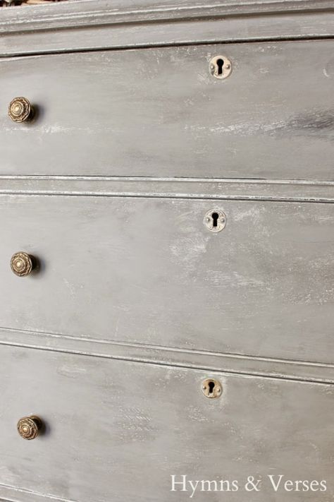 an old dresser is painted gray and has knobs on it