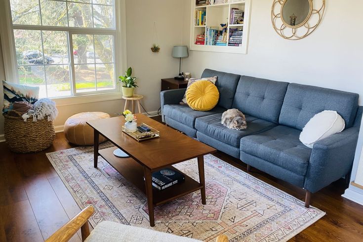 a living room filled with furniture and a wooden table in front of a large window