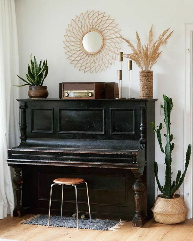 there is a piano in the living room with plants on the shelf next to it