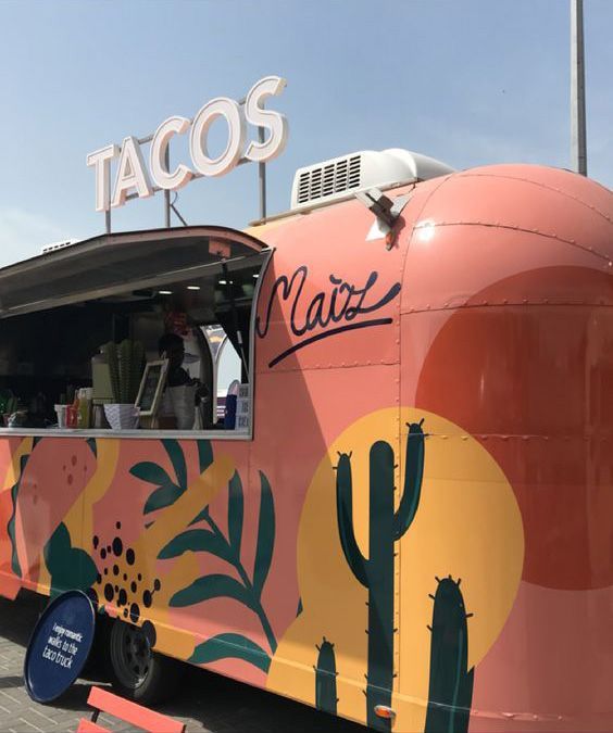 a taco truck parked in front of a building with cactus designs on the side