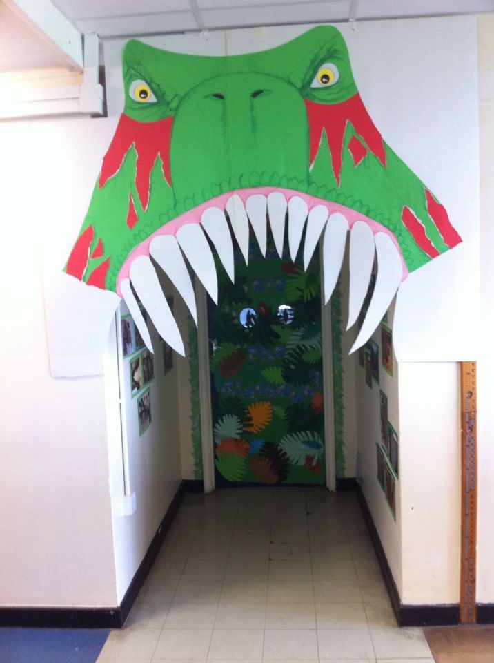 a large green monster head hanging from the side of a hallway