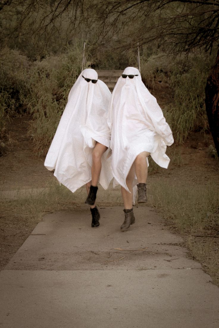 two people dressed in white walking down a path