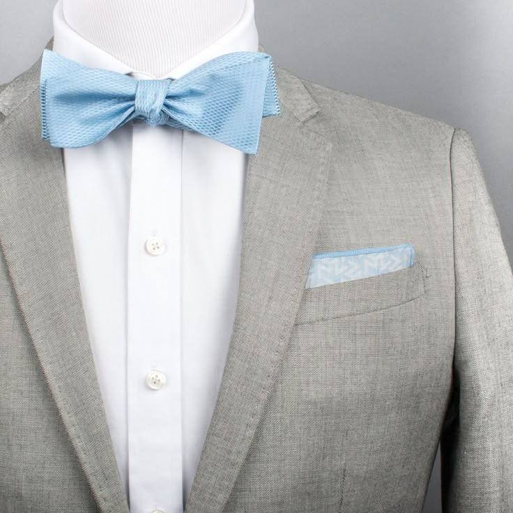 a man wearing a gray suit with a light blue bow tie and pocket square on his lapel