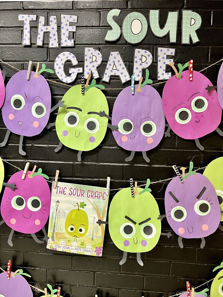 a bulletin board with the words the sour grape on it and some paper cutouts hanging from clothes pins