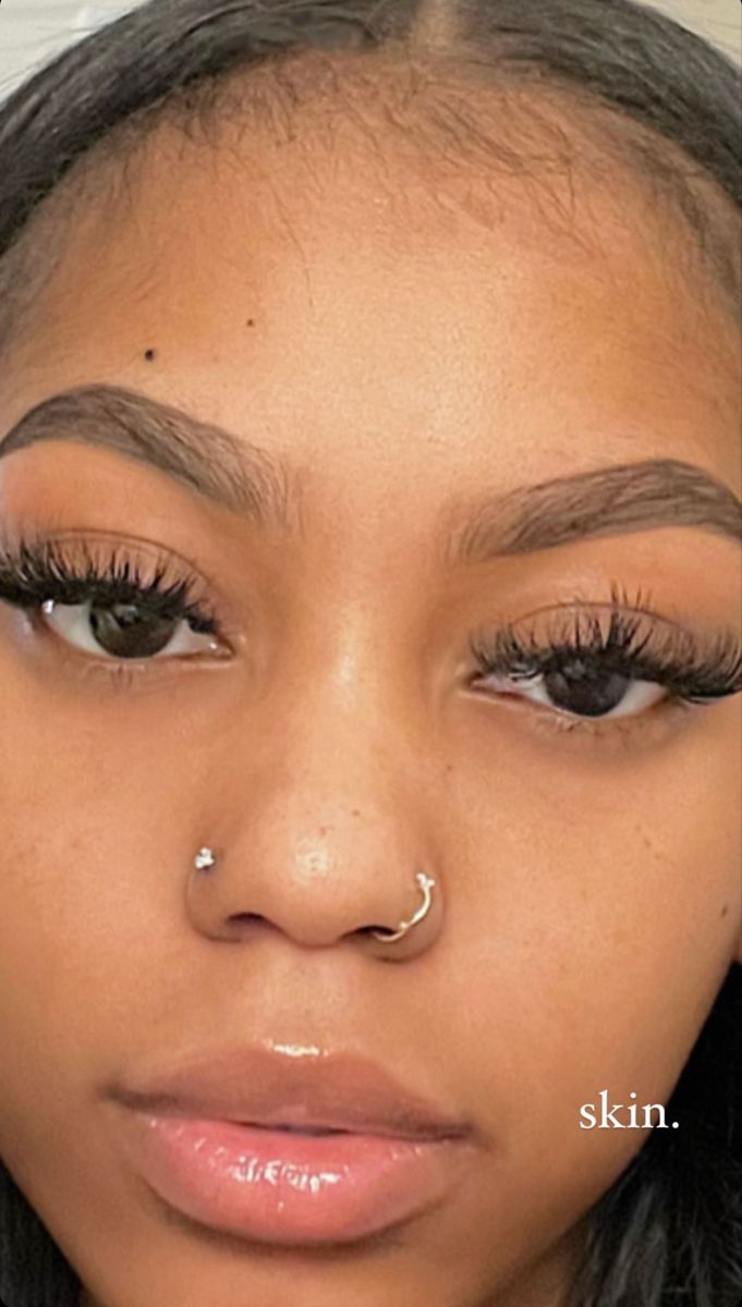 a woman with long lashes and piercings on her nose