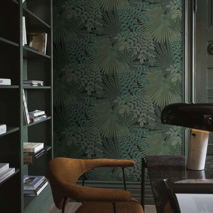 a room with green wallpaper and a chair in front of a book shelf filled with books