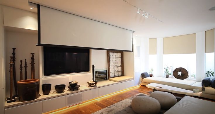 a living room with white couches and a flat screen tv mounted on the wall