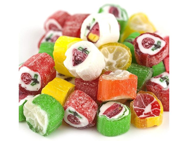 a pile of assorted candy on top of each other with lemons and strawberries