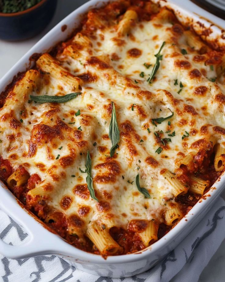 a casserole dish with cheese and herbs in it on a white tablecloth