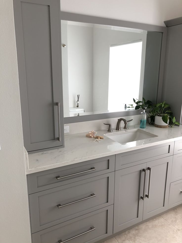 a large bathroom with gray cabinets and white counter tops is seen in this image from the front view