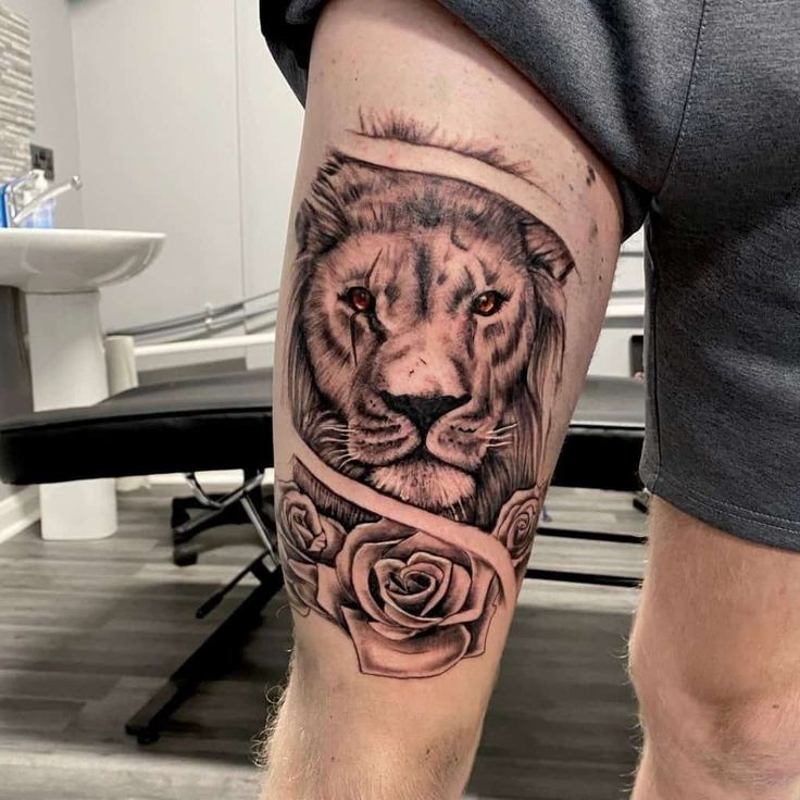 a man's leg with a lion and rose tattoo on the side of his leg