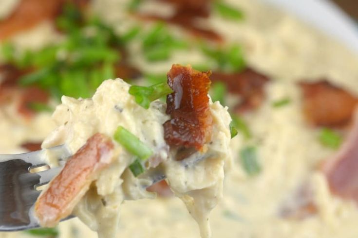 a close up of a spoon full of food with bacon and celery on it