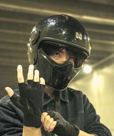 a man wearing a black helmet and holding his hand up