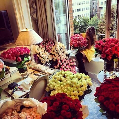 a woman sitting in a room filled with lots of flowers