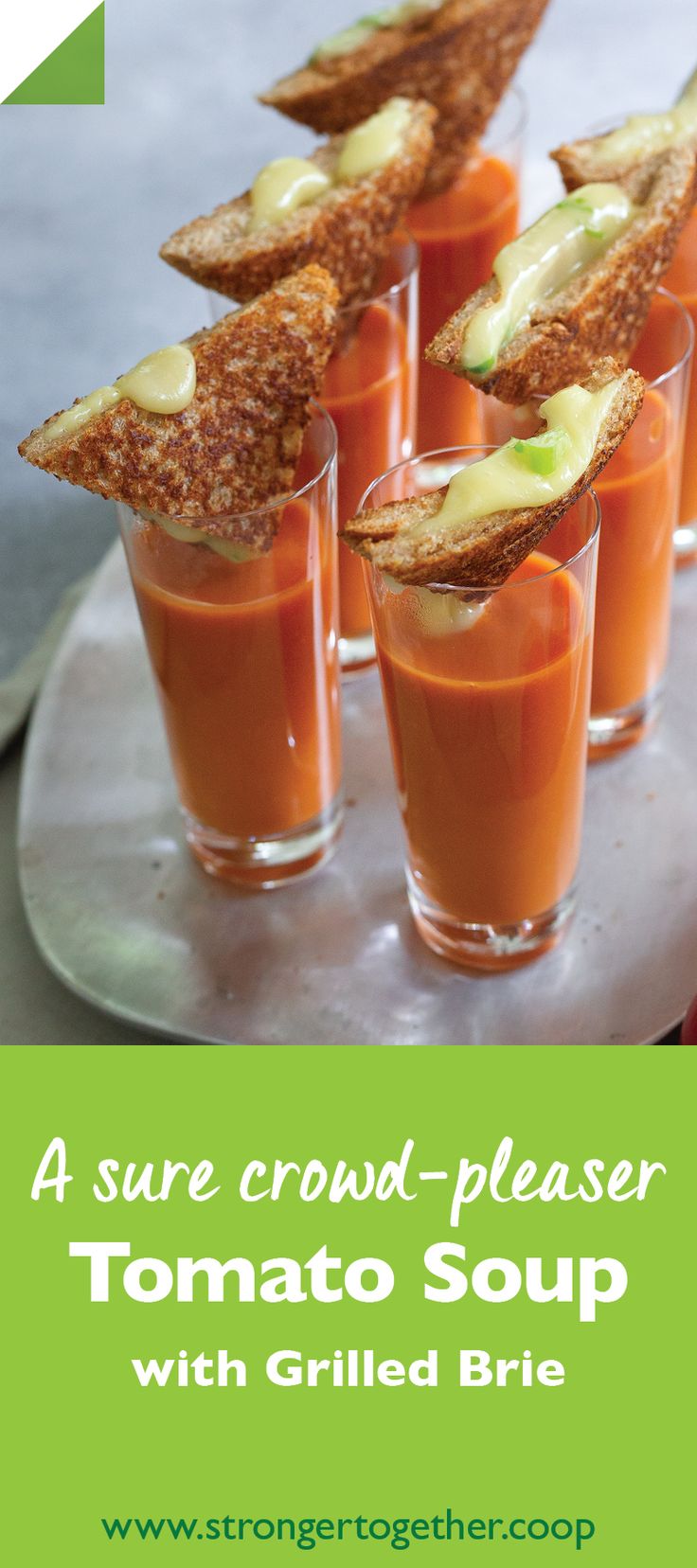 four small cups filled with tomato soup and topped with crackers on a white plate