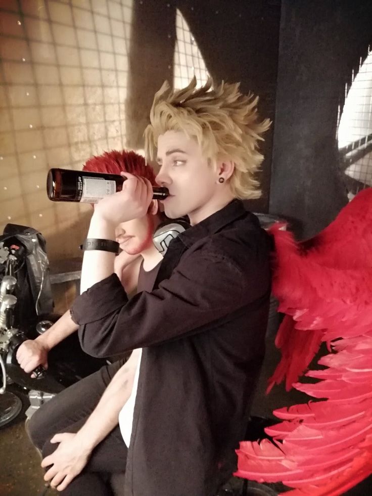 a young man taking a photo with his cell phone while sitting on a bench next to an angel