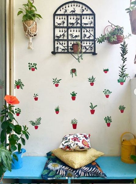 a blue table topped with lots of potted plants next to a wall mounted clock