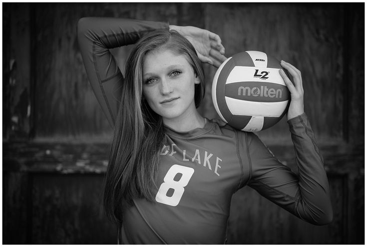 black and white photograph of a woman holding a volleyball in front of her head with one hand