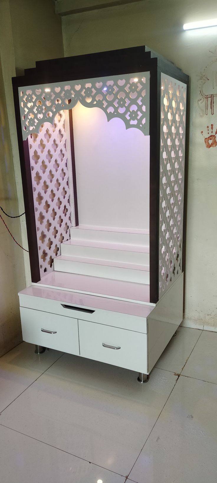 a white bed with drawers underneath it in a room that has tile flooring and walls