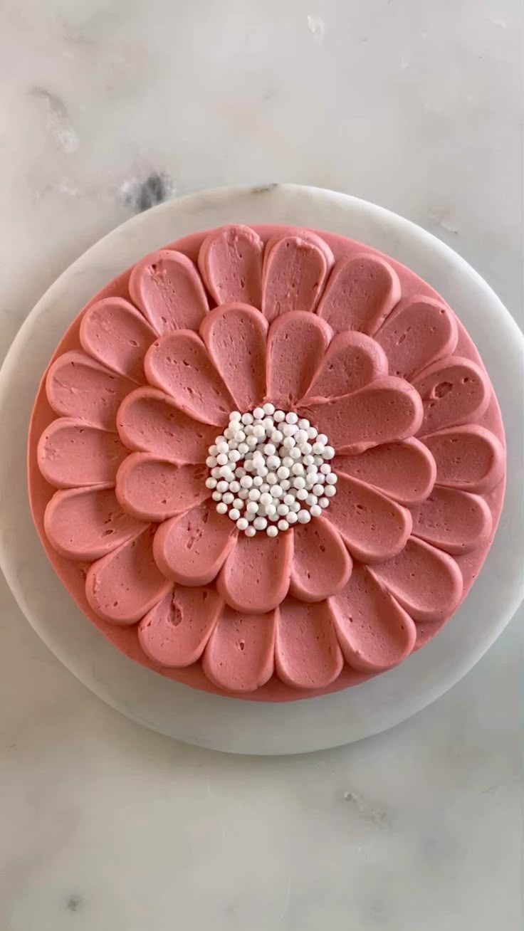 a cake with pink frosting and white sprinkles sitting on a plate