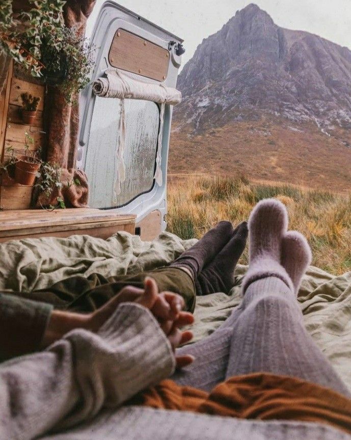 a person laying on top of a bed next to a tv set in the mountains